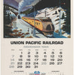 Load image into Gallery viewer, Vintage Union Pacific Railroad calendar page from December 1969, featuring a painted winter mountain scene with a yellow and gray passenger train, plus printed calendar grids and railroad logos.
